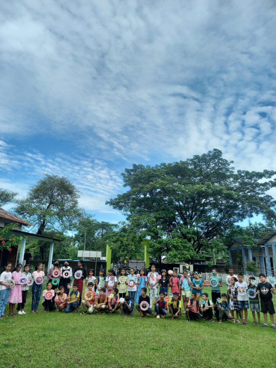 A large group of students holding paper mandalas on the school field