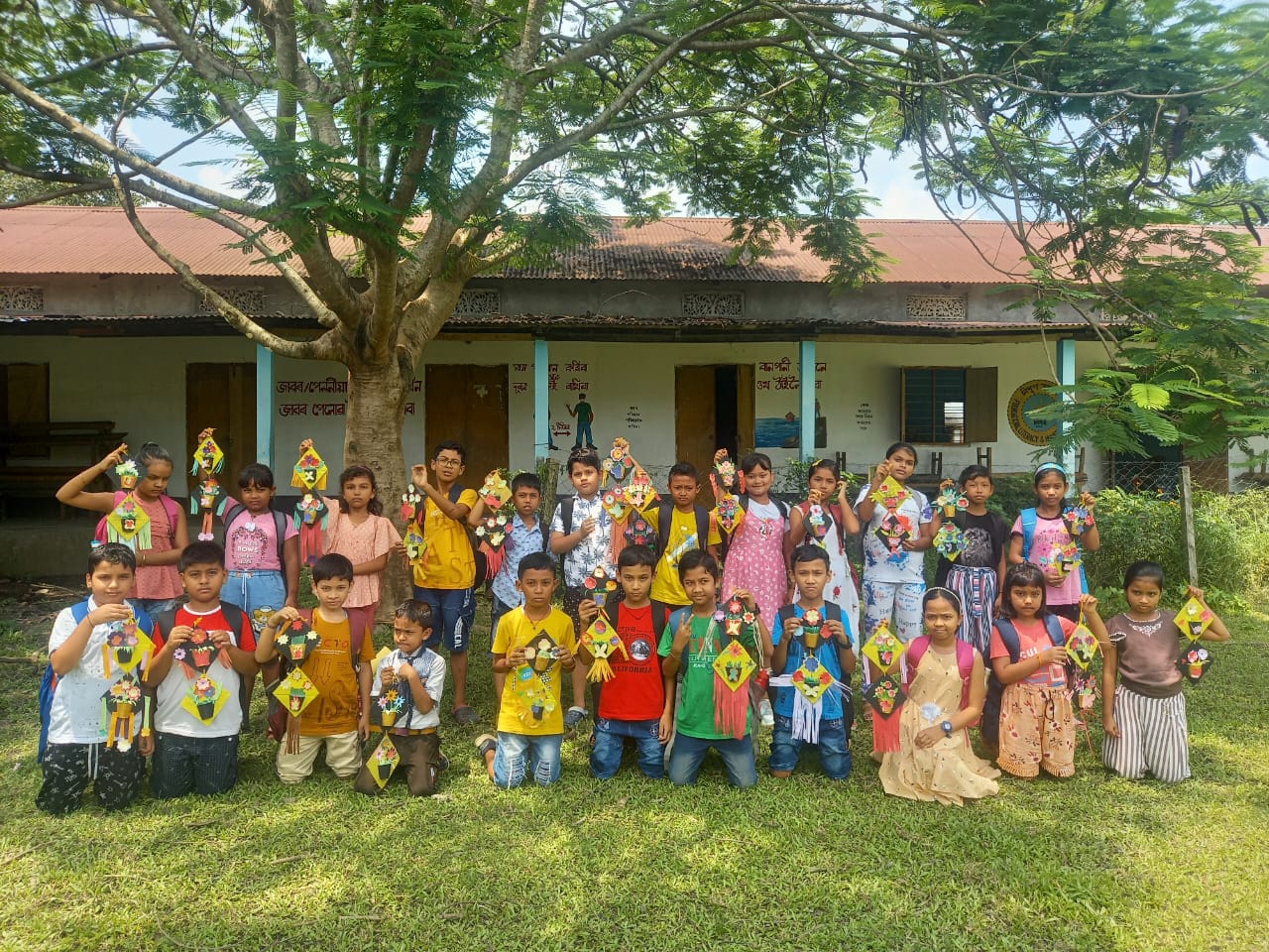 Students holding their finished paper kite crafts outside the school