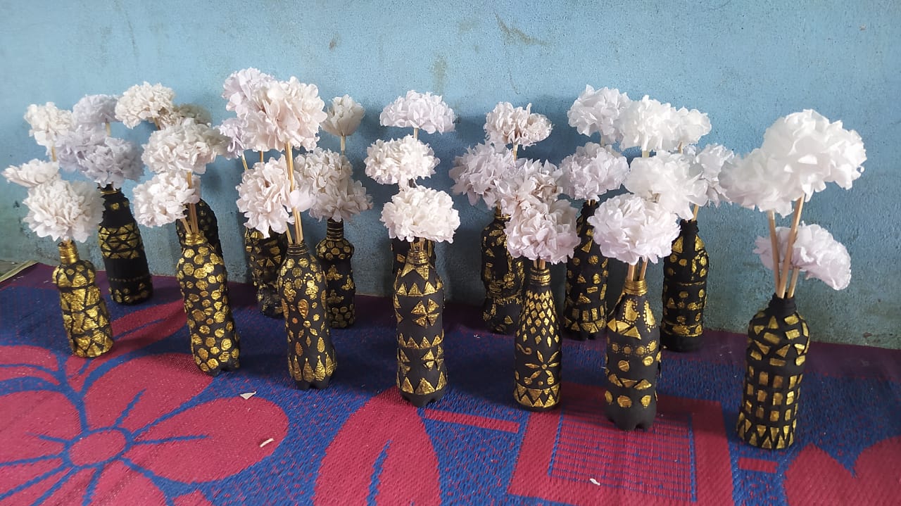 Painted black and gold bottles holding white paper flowers