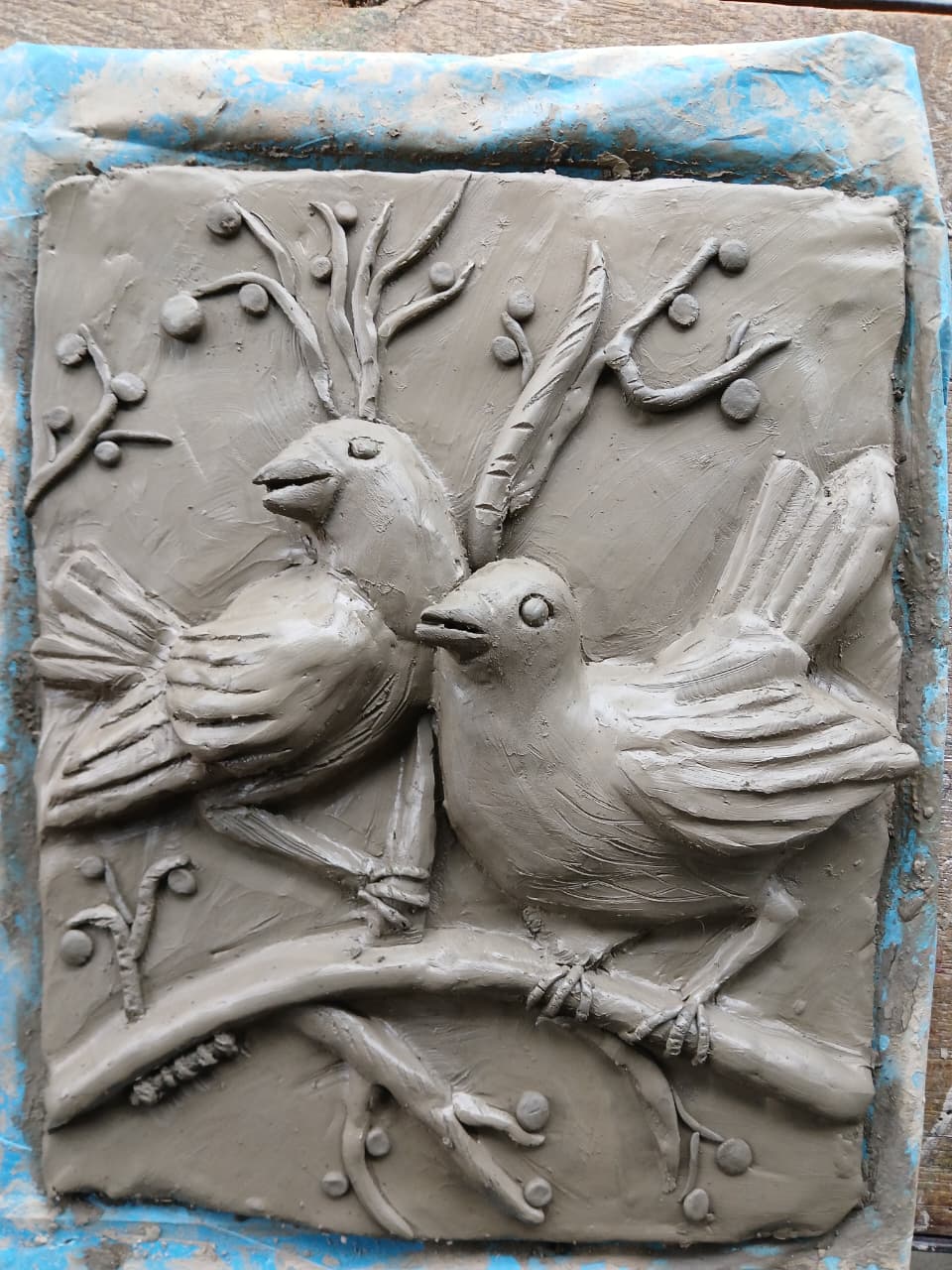 Clay relief panel of two birds on a branch
